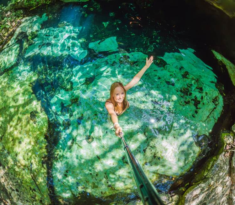 Woman immersed in the enchanting beauty of a Mexican cenote, surrounded by crystal-clear waters and captivating natural formations