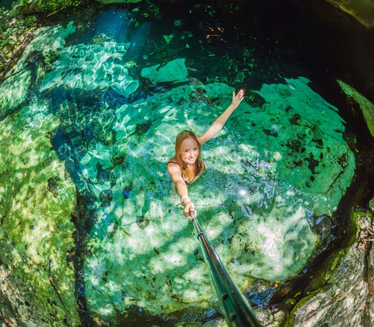 Tulum launches sustainable cenote route with 12 certified sites - Photo 2 Woman immersed in the enchanting beauty of a Mexican cenote, surrounded by crystal-clear waters and captivating natural formations