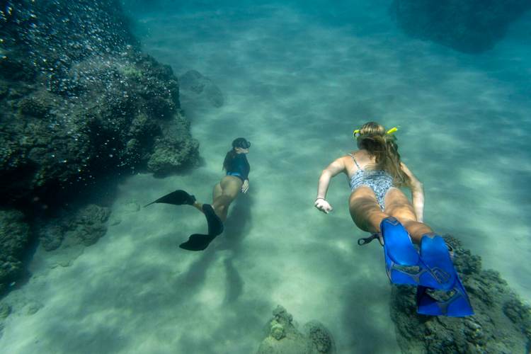 women-freediving-with-flippers-underwater