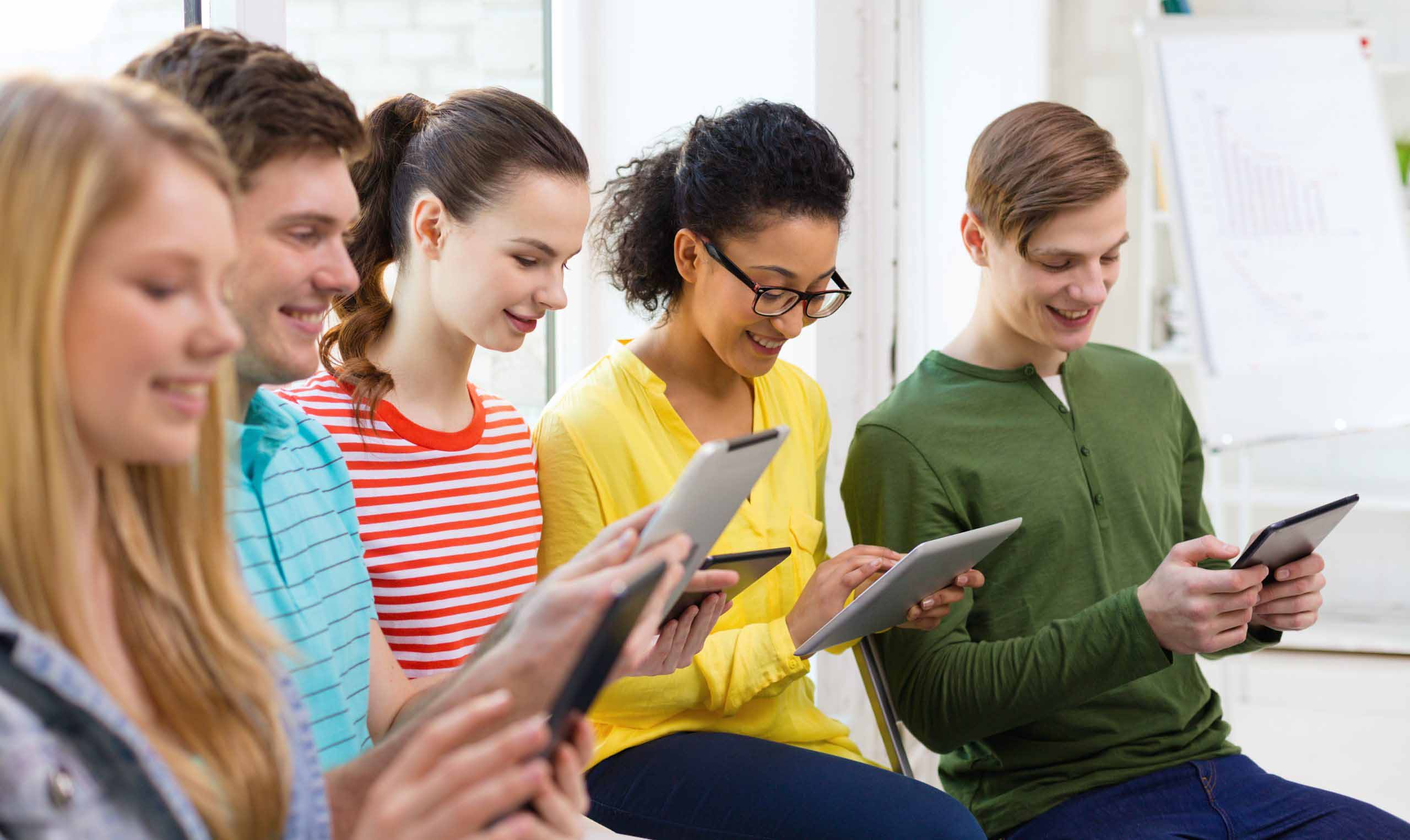 Smiling students with tablet pc at school