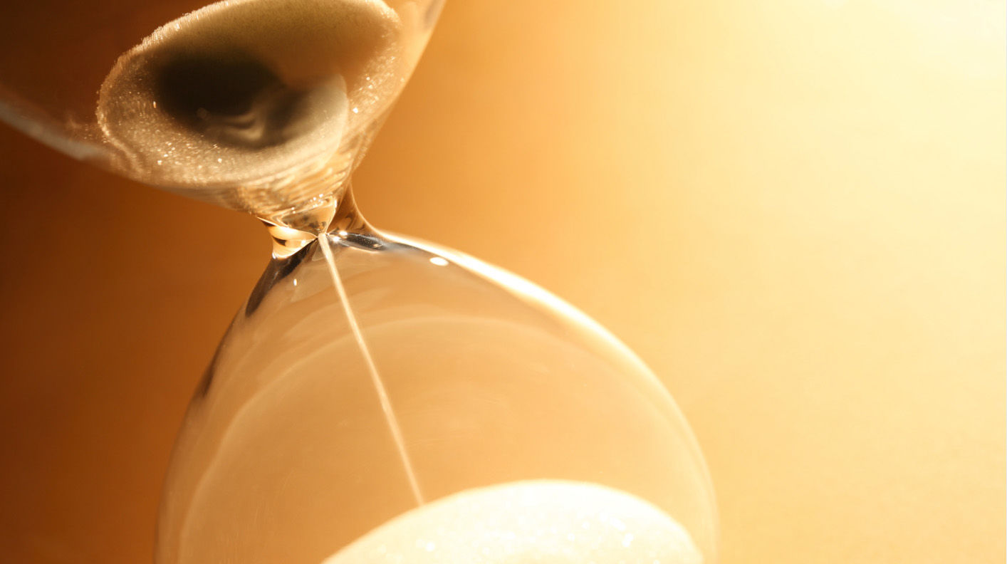 Hourglass on an orange backround with the light coming from the right corner.