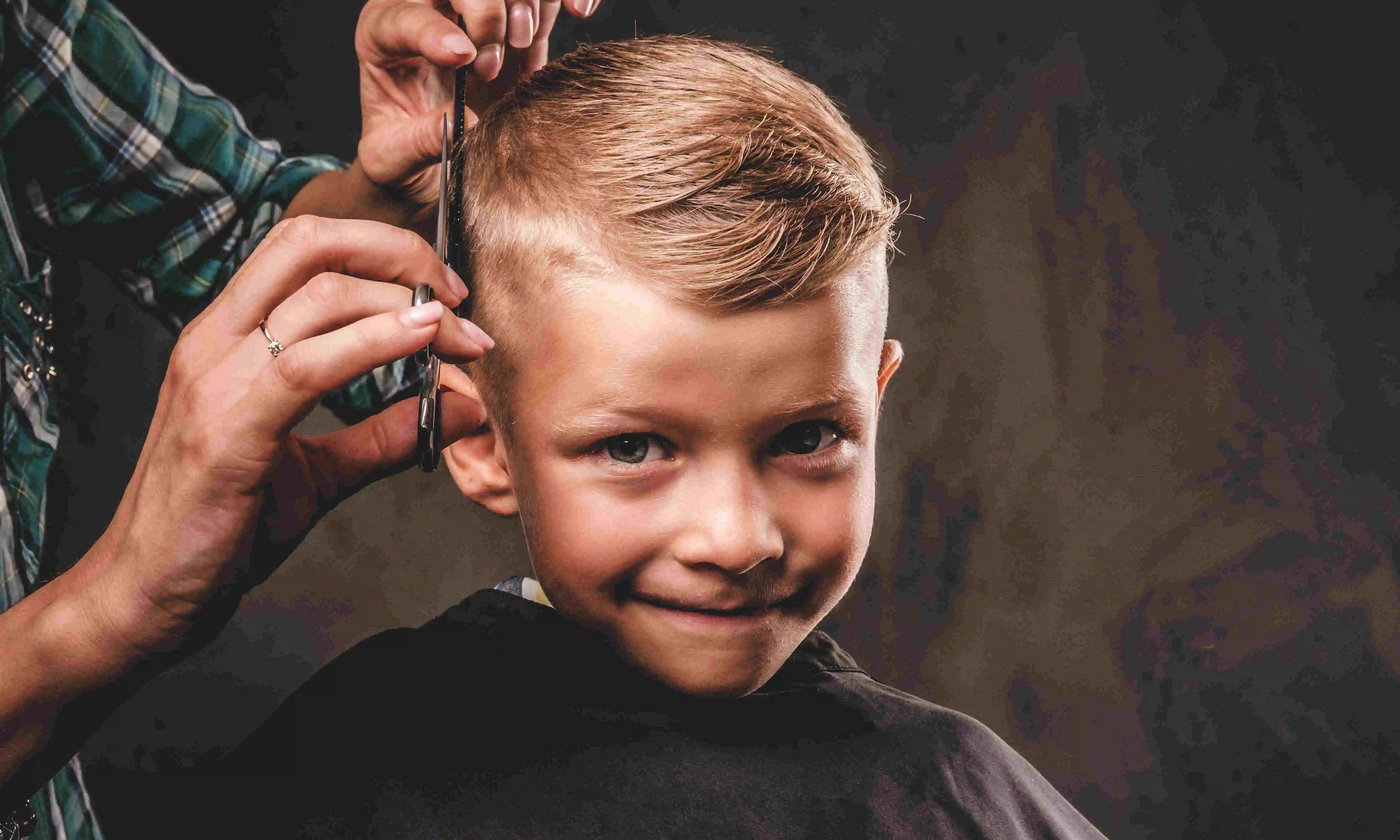 Young boy smiling during his home haircut by a mobile barber in Dubai.