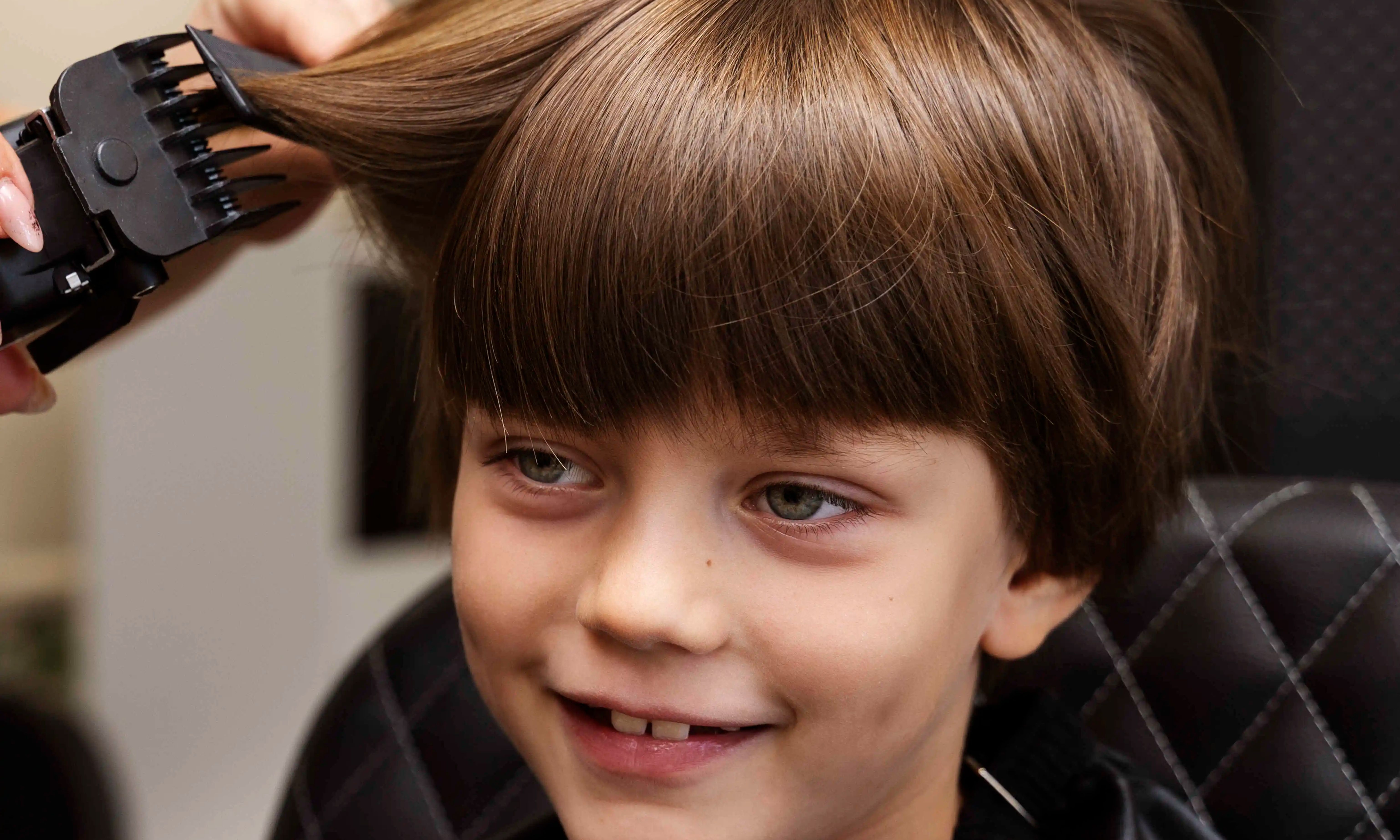 Parent watching as a professional barber cuts their kid’s hair at home.