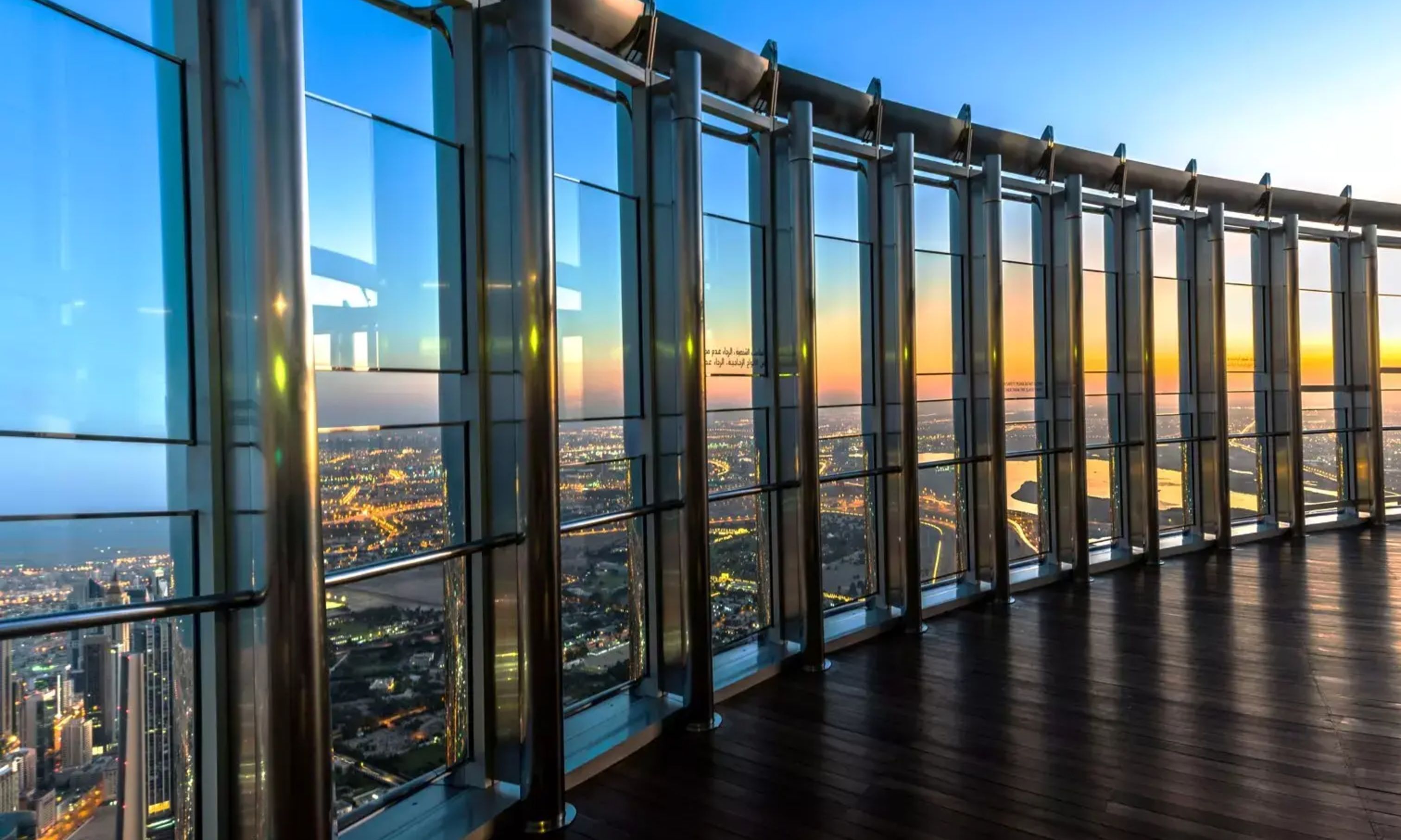 Burj Khalifa observation deck, capturing panoramic skyline views through glass panels at sunset.