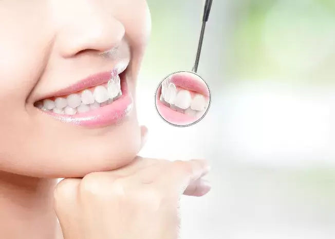 A Winchester TN Dentist holding a mirror against a lady's teeth