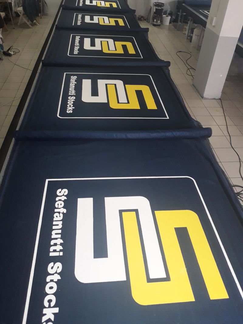 Printed shadenet fence branding along a road frontage