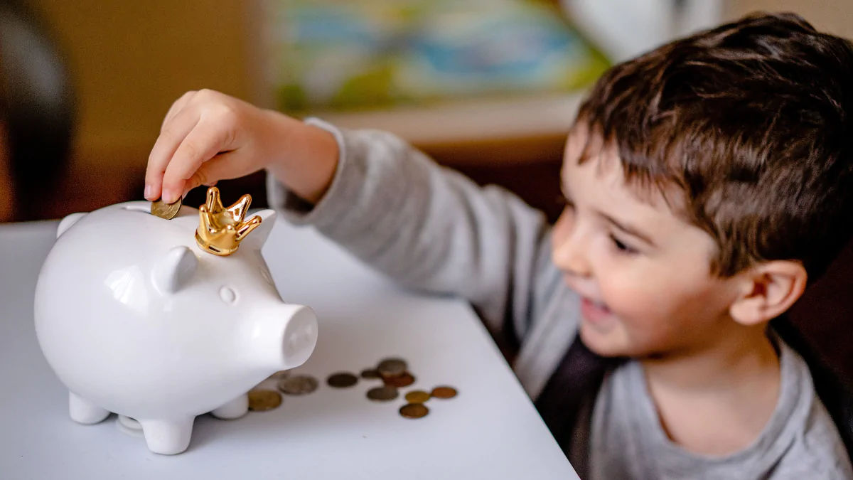 Criança colocando moedas dentro de um cofrinho
