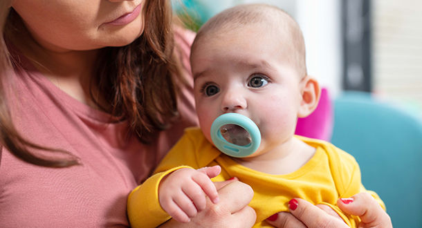 Baby sat on mothers lap sucking on break-like Pacifier