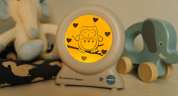 Groclock on bedside table amongst toys