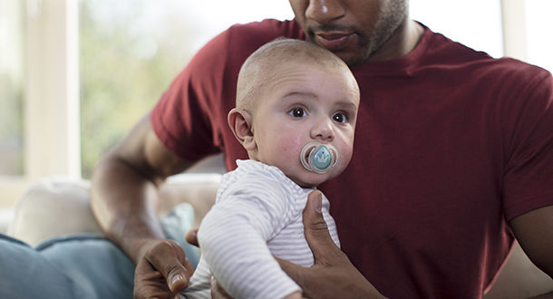 Father holding baby who is sucking on night time soother