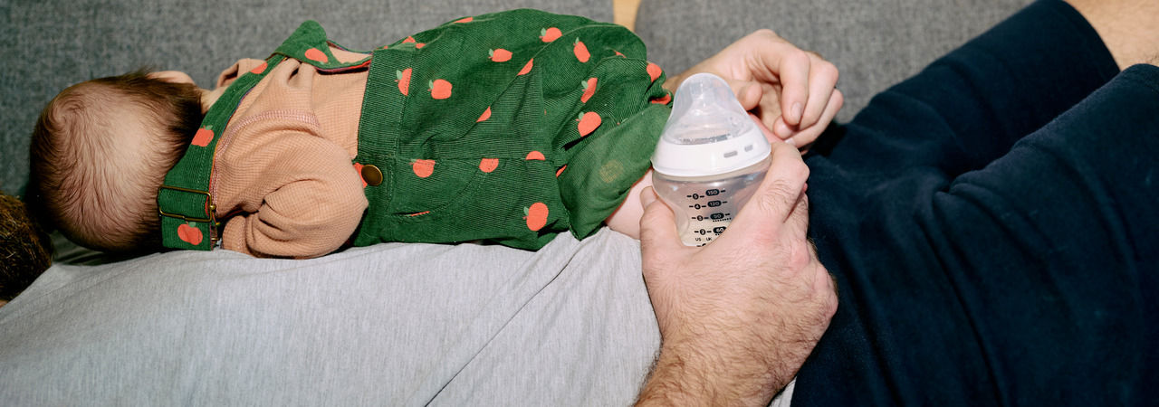 Father holding Natural Start bottle and baby lying on fathers chest