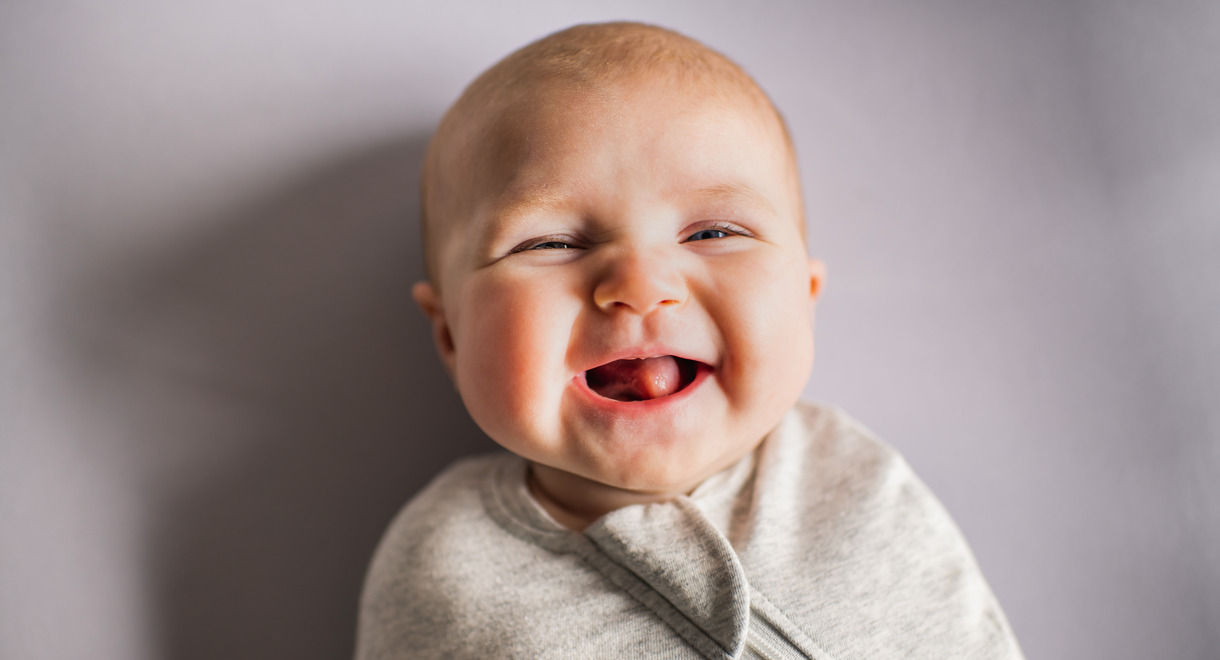 Close up of baby smiling wearing Swaddlebag