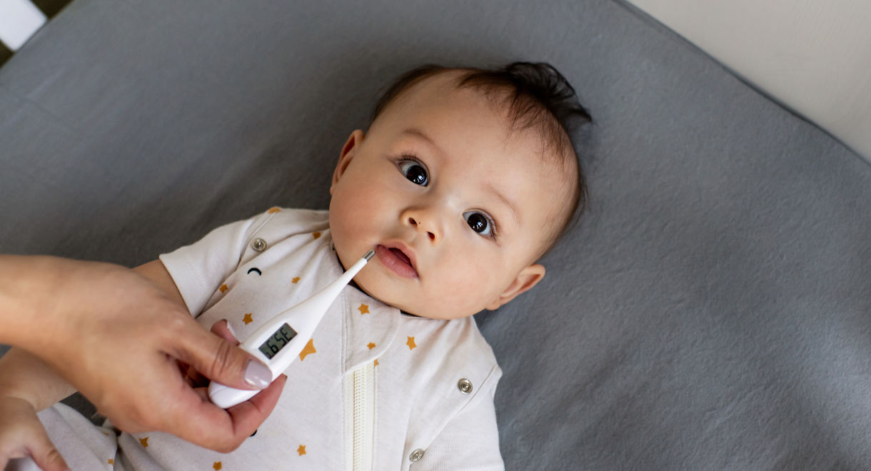 Mother using thermometer on baby lay down