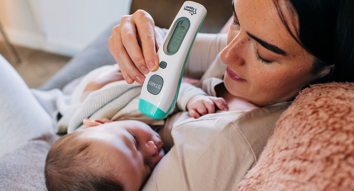 Mother holding baby and using NoTouch thermometer to take baby's temperature