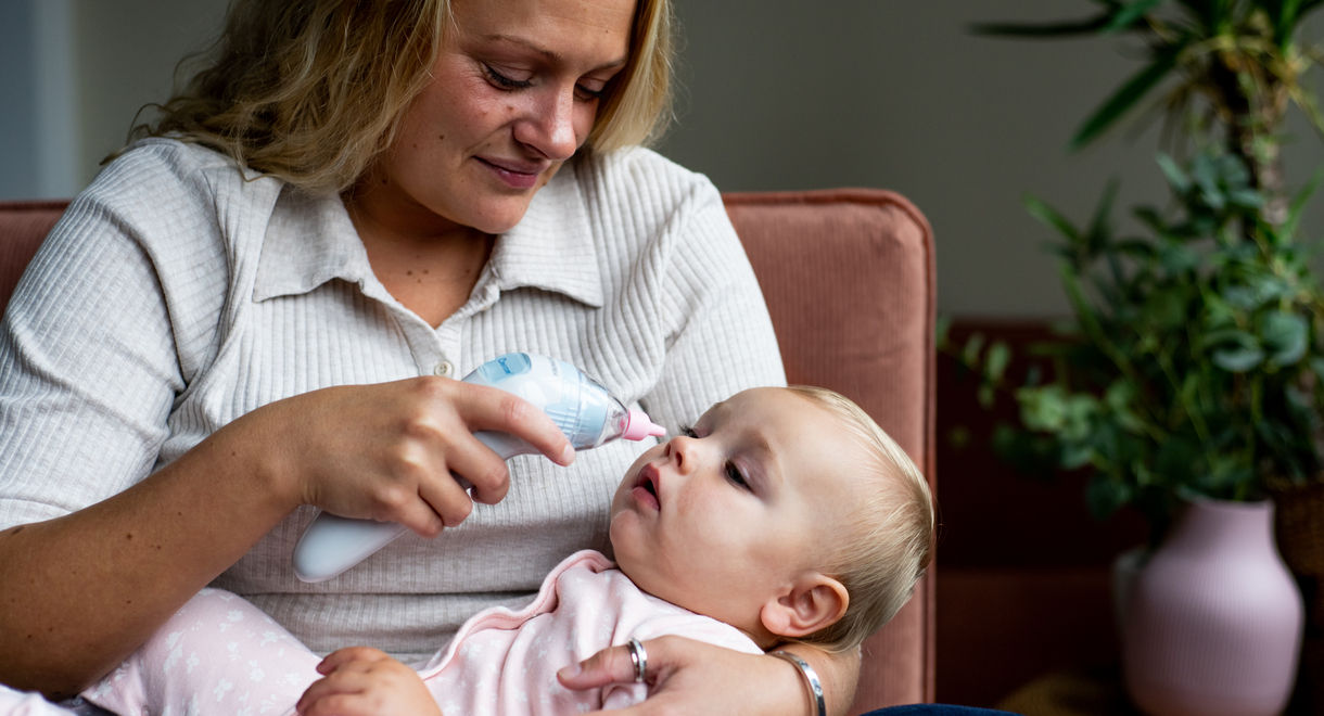 Women using nasal Aspirator on baby who is in her arms