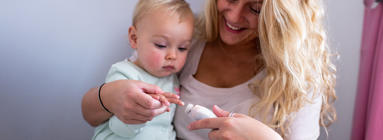 Women trimming baby's nail with nail trimmer