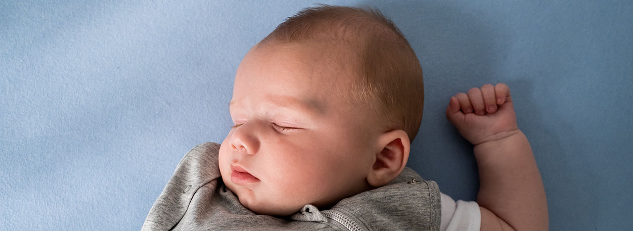 Baby sleeping wearing grey sleepbag