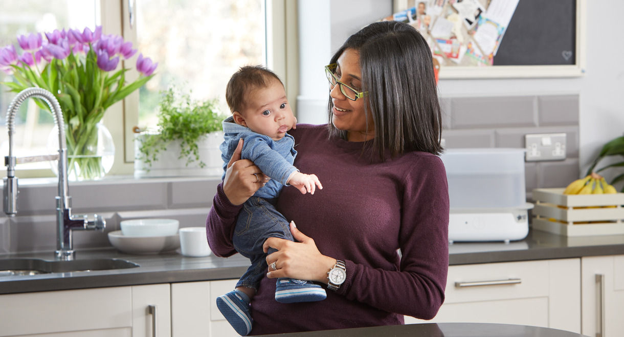 Mother carrying baby in kitchen 