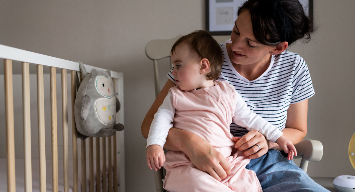 Baby sat on mother knee looking at Grofriend light and sound sleep aid 