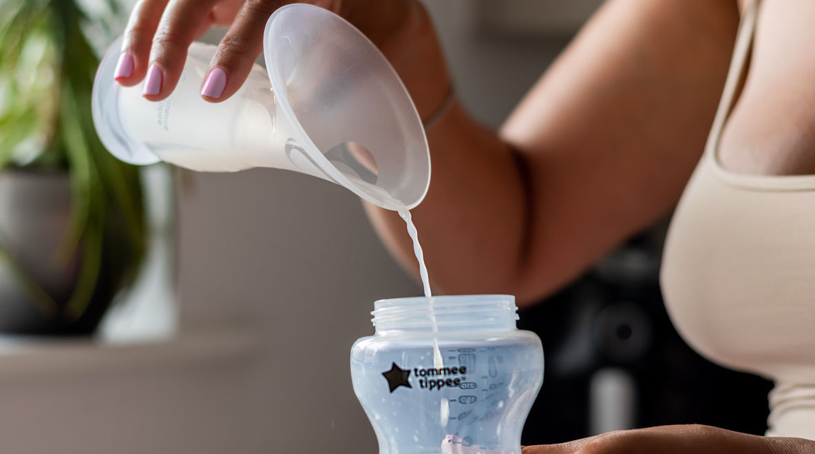 Mother pouring milk from silicone breast pump into Natural Start bottle