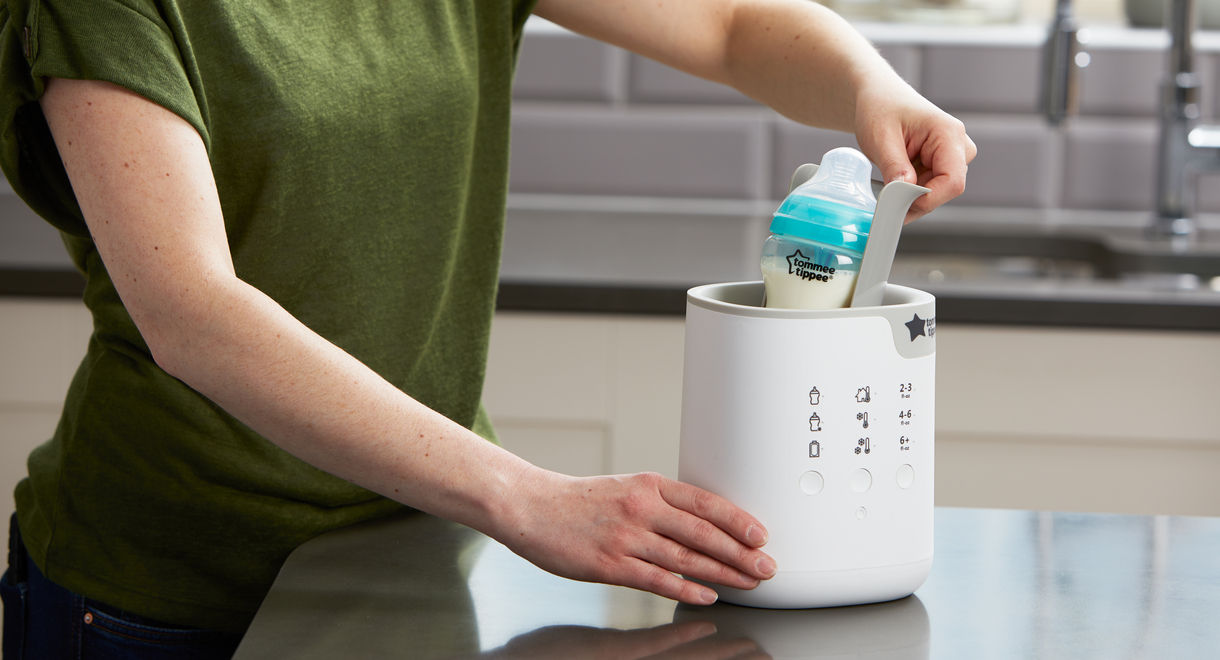 Mother pulling Advanced anti-colic bottle out of Multiwarm Intuitive Milk Warmer