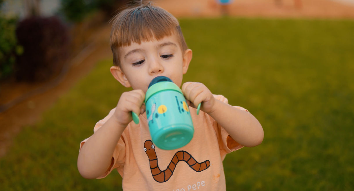 Toddler drinking from green weighted straw cup