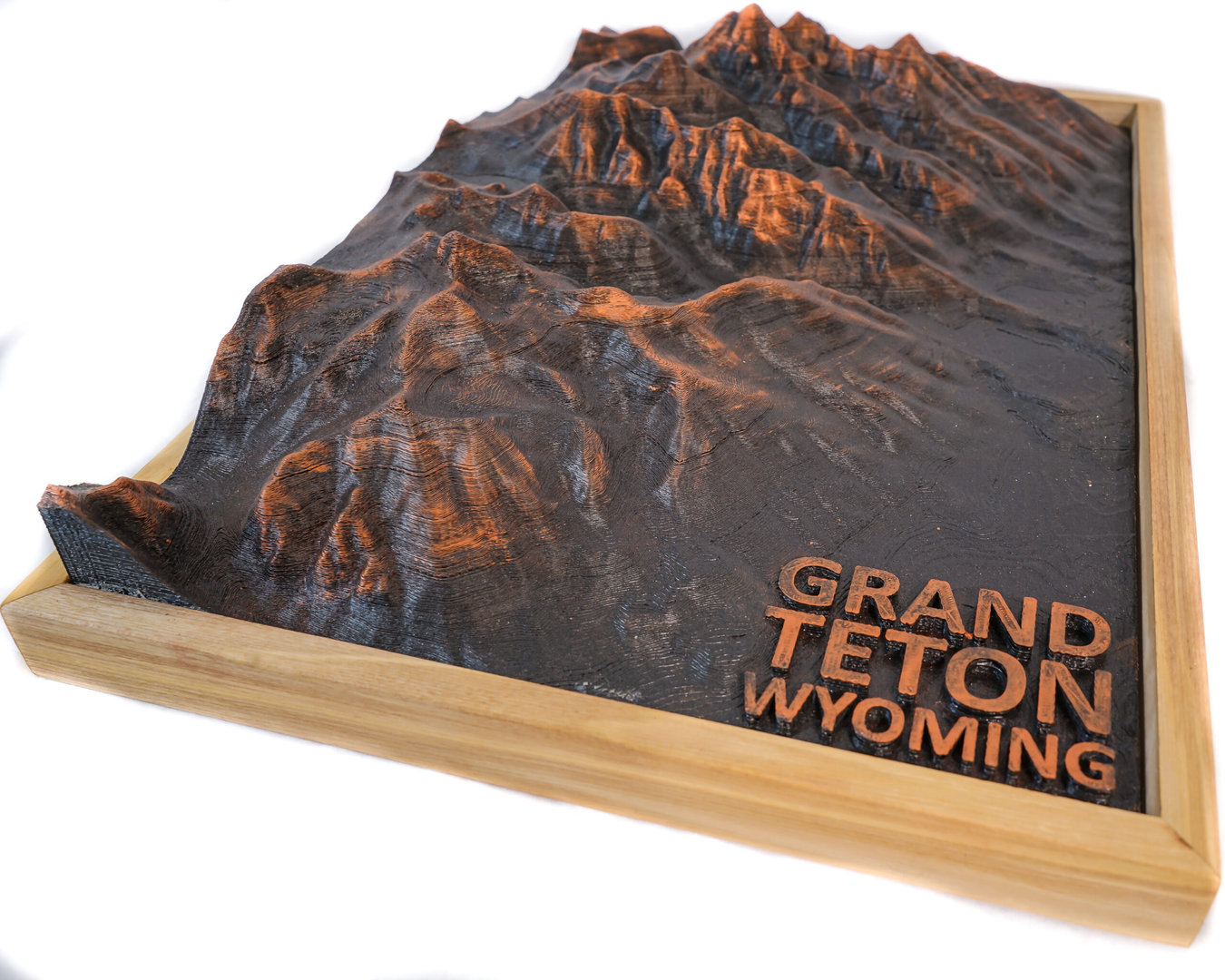 Side-lit close-up of an FDM-printed mountain range showing stepped layer lines