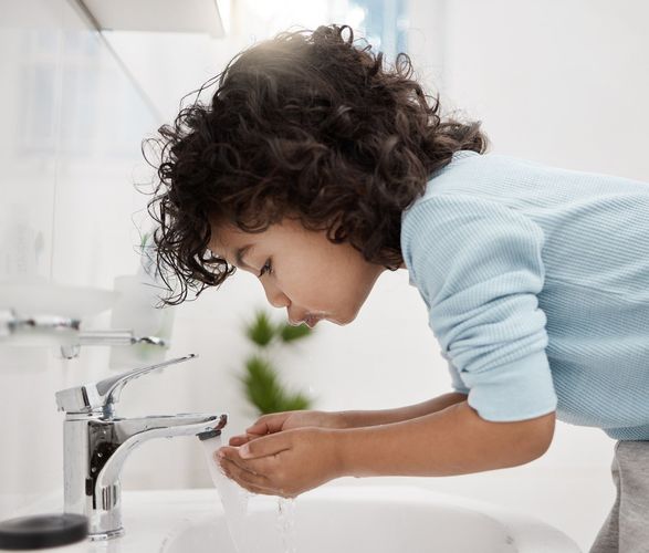 10 Essential Dental Hygiene Tips for 2025 6 Shot of an adorable little boy washing his hands and mouth at a tap in a bathroom at home