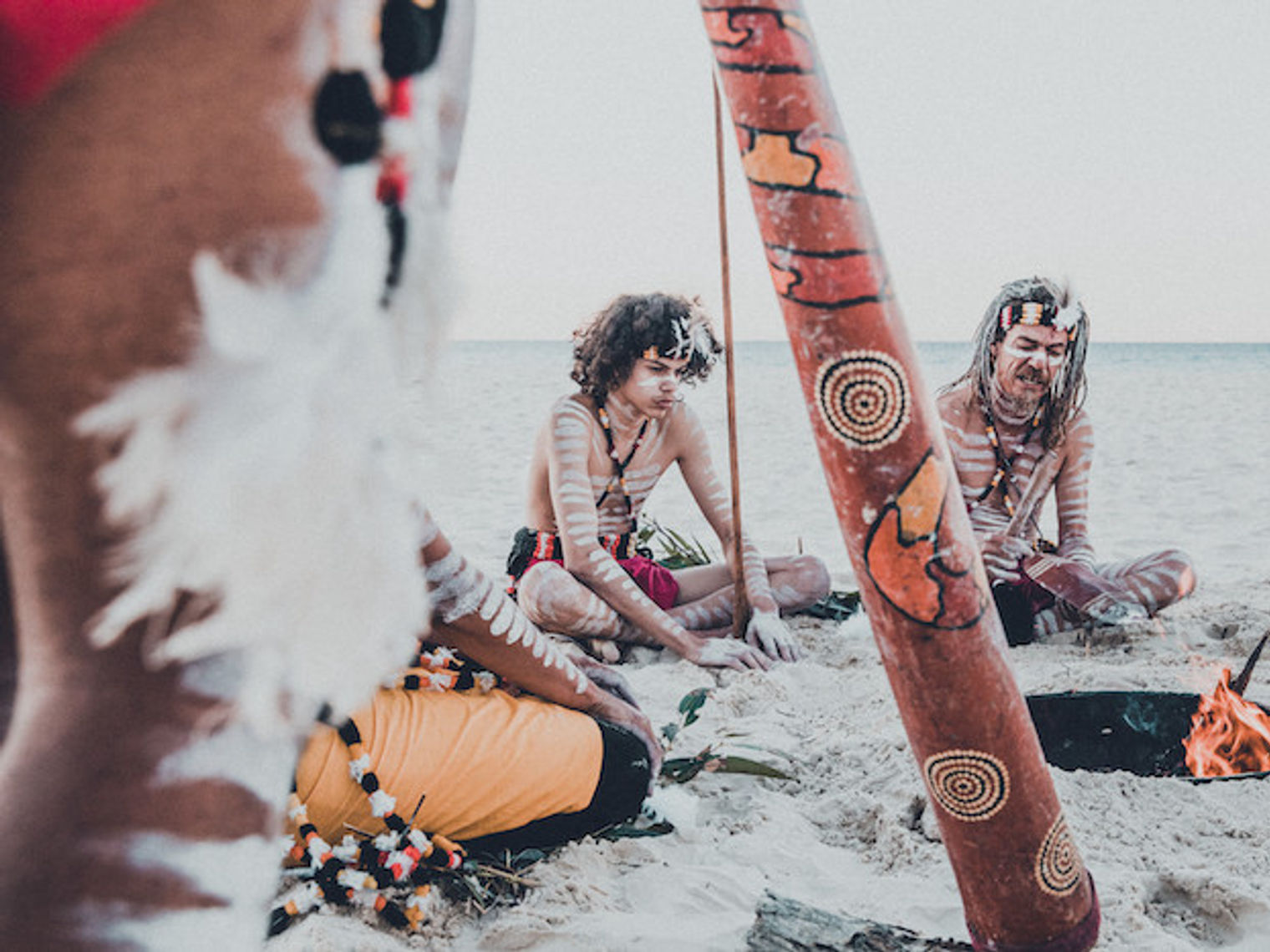 Een groep mensen met bodypaint zittend rond een vuurtje kust van Redland, Australië