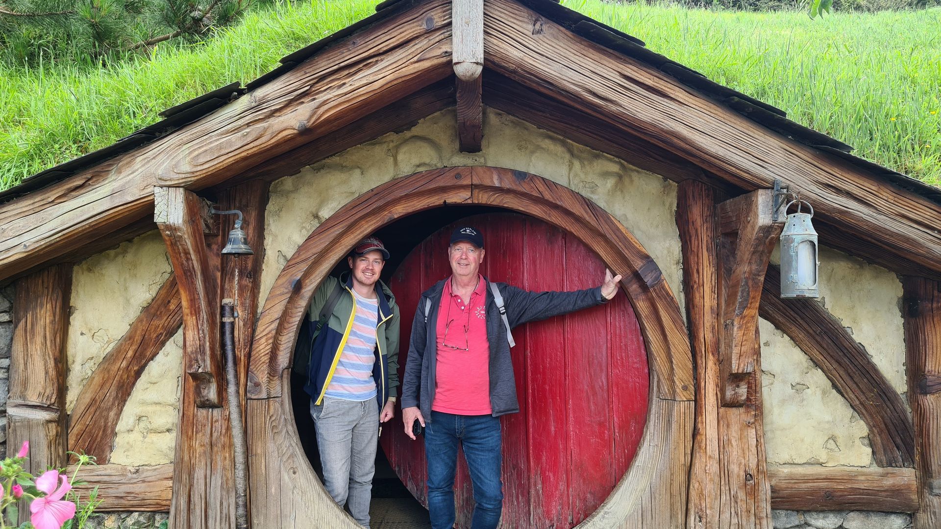 TravelEssence klanten poseren voor een ronde hobbitholdeur in Hobbiton, Nieuw-Zeeland
