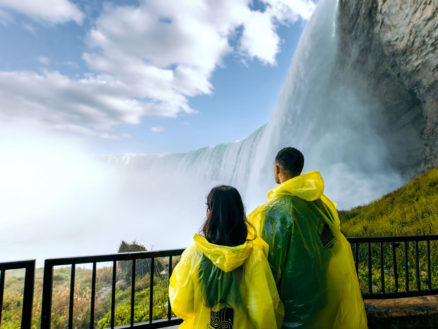 Ein Paar in wasserdichten Ponchos blickt auf die tosenden Niagarafälle in Kanada.