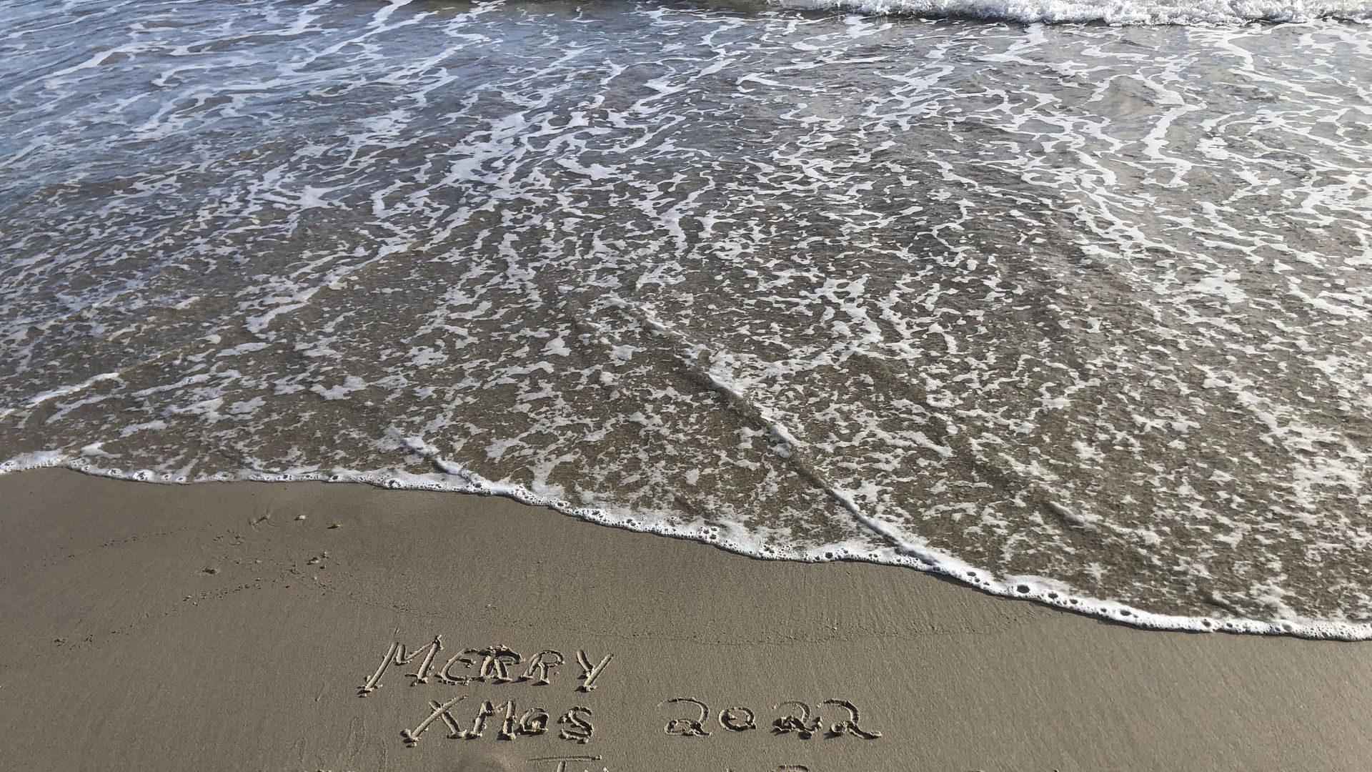 "Merry Xmas TravelEssence" in den Sand geschrieben an einem Strand in Westaustralien
