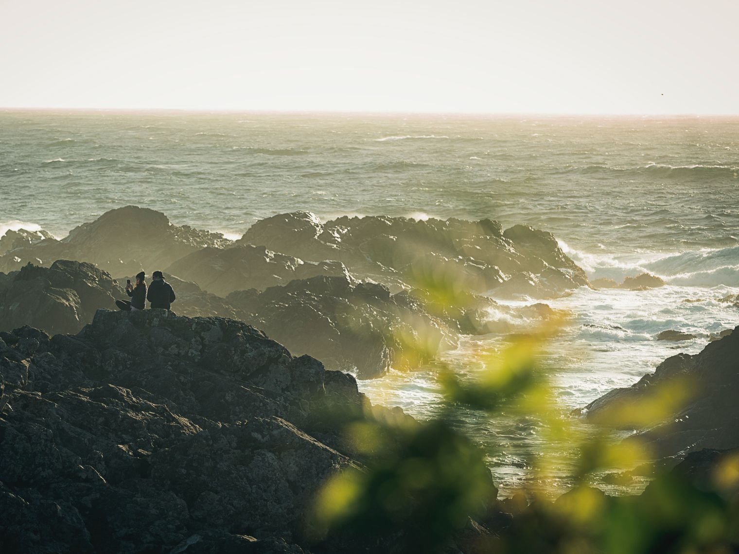 Paar sitzt auf steiniger Küste in Pacific Rim