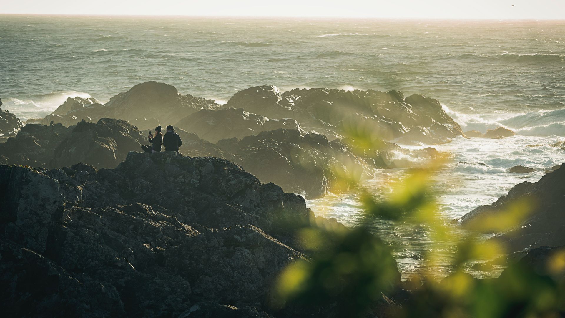 Paar sitzt auf steiniger Küste in Pacific Rim