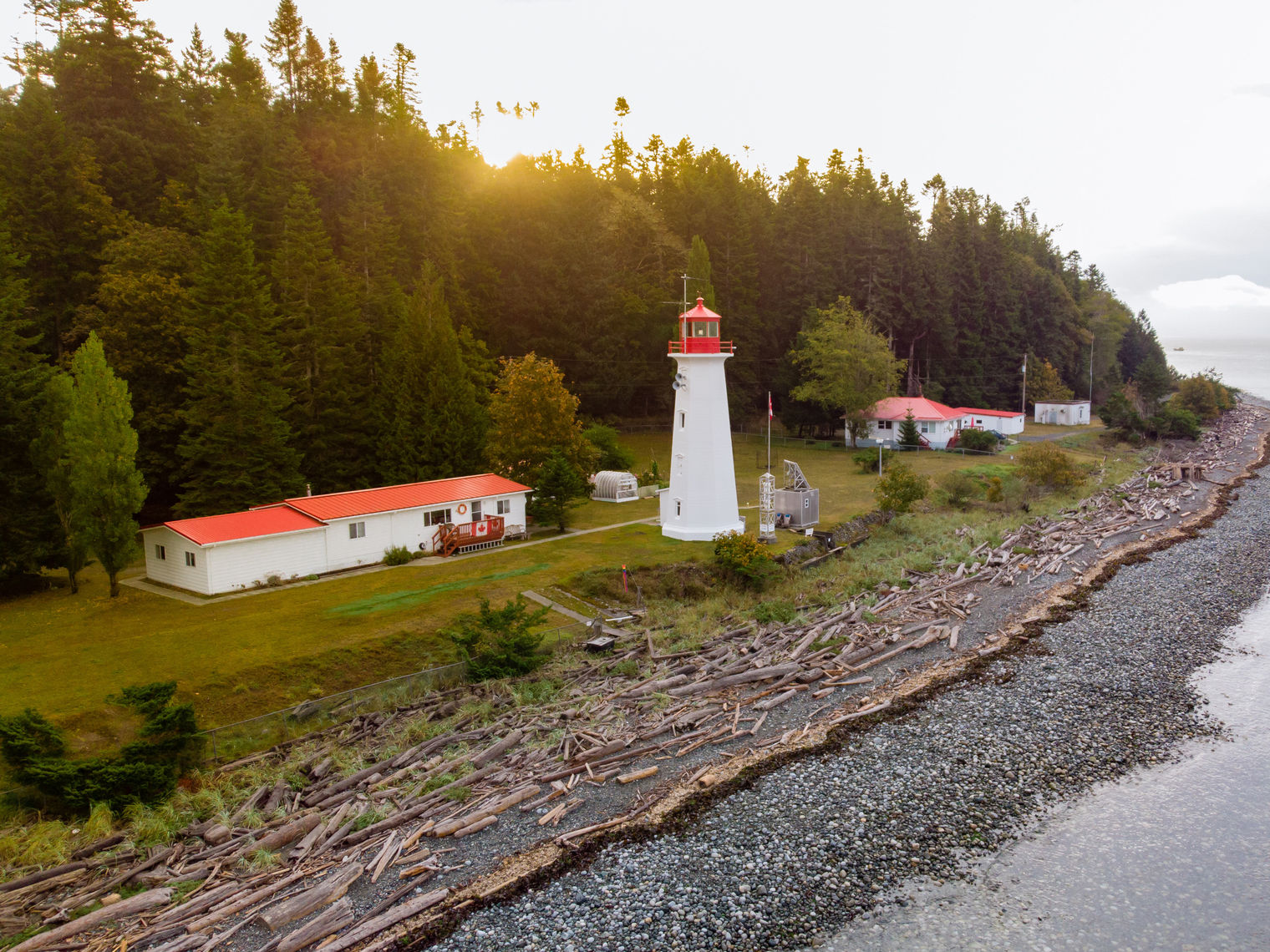 A white lighthouse on a forested shoreline on Quadra Island, Canada
