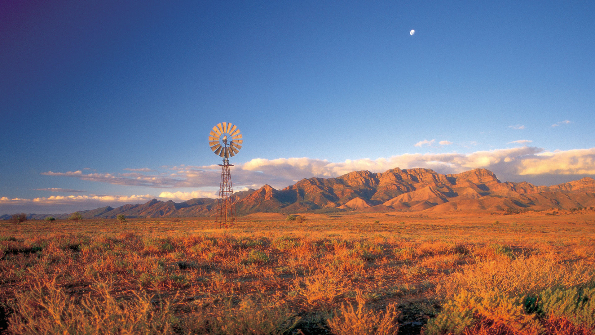 Oude windmolen bij zonsondergang voor de roodgekleurde heuvels van de Flinders Ranges, Zuid-Australië