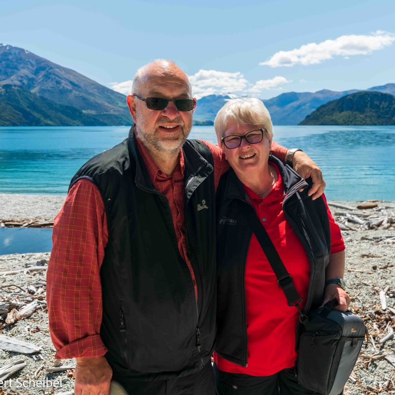 A couple of customers smile in front of Lake Wanaka