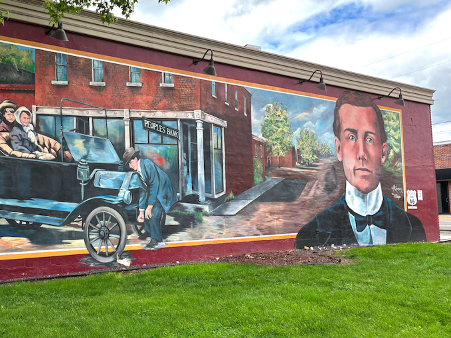 Historisches Wandgemälde an der Route 66 mit einem Oldtimer, historischen Figuren und großem Porträt