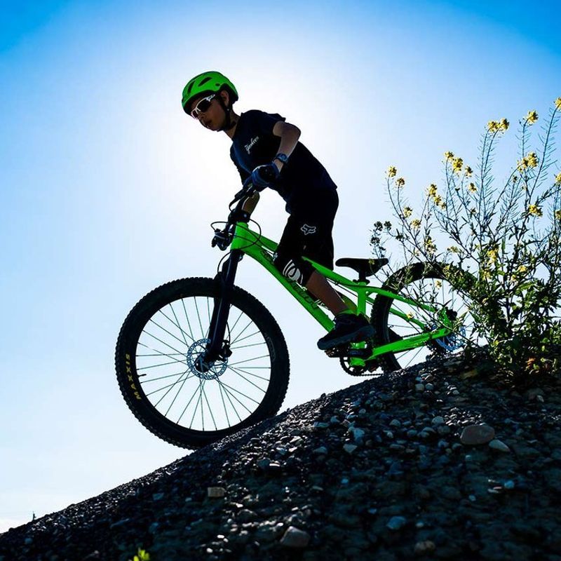 Fietser op een gifgroene fiets die klaarstaat om een afdaling te maken