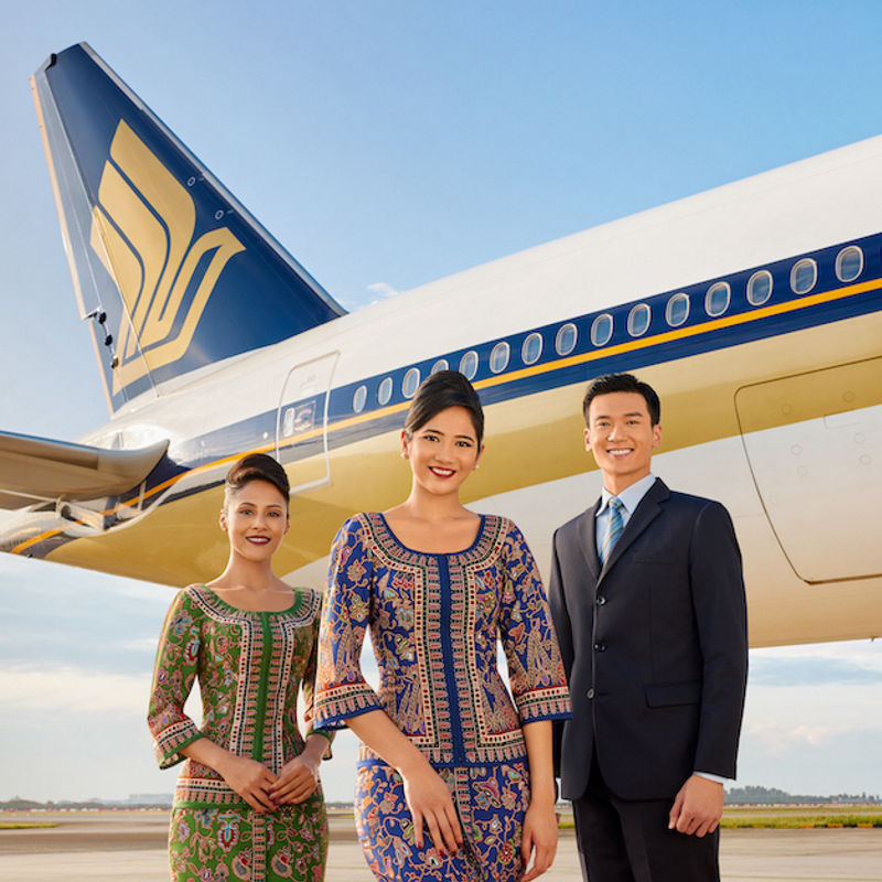 Die Crew der Singapore Airlines lächelt vor einem Flugzeug in die Kamera