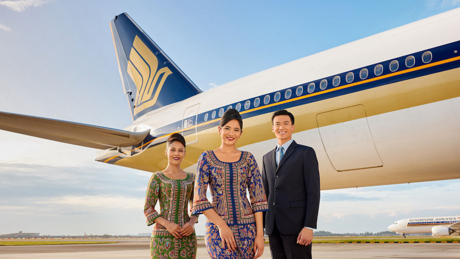Die Crew der Singapore Airlines lächelt vor einem Flugzeug in die Kamera