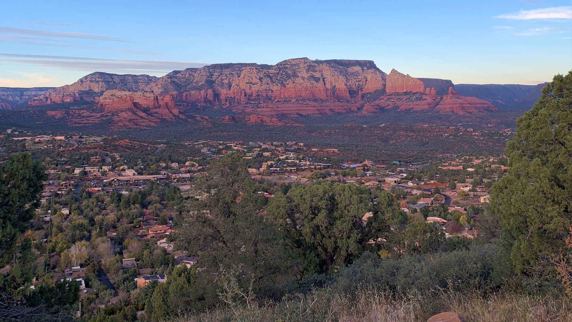 Aerial view of Sedona's red rock formations rising above the town at sunset