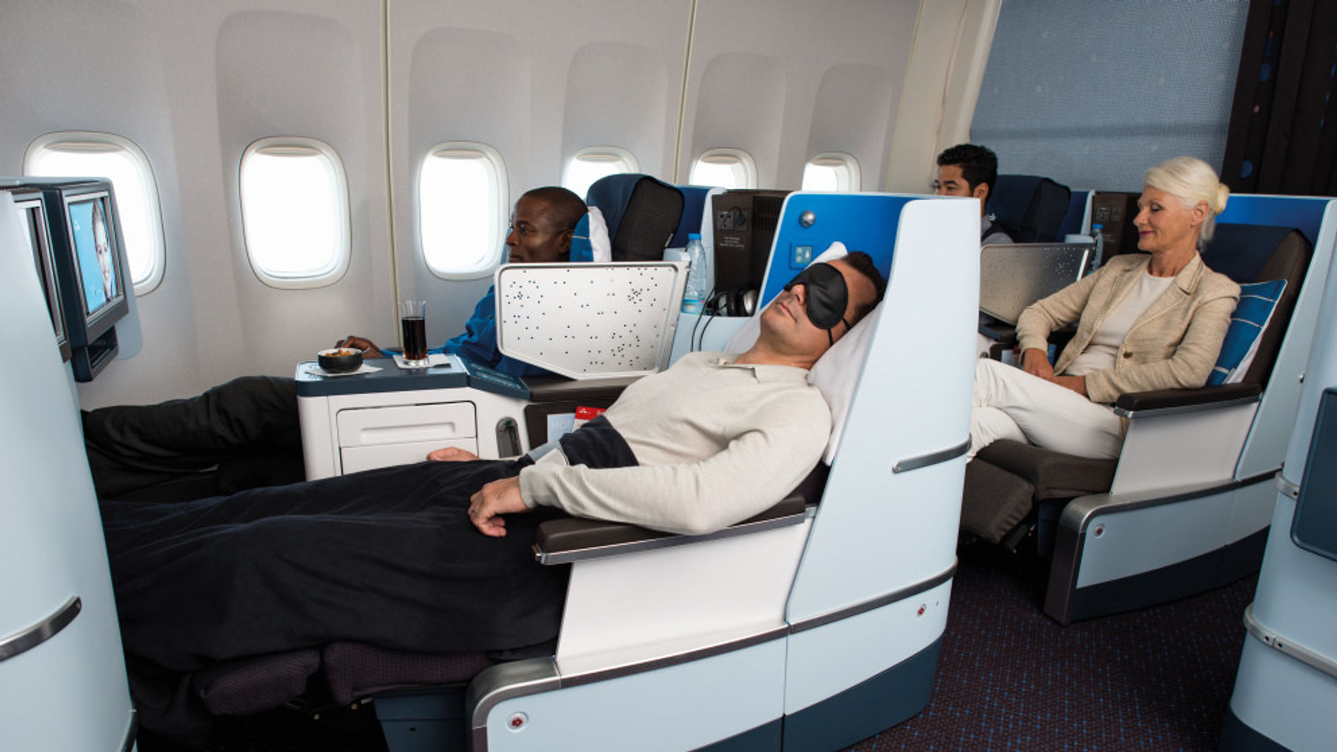 Die Passagiere entspannen sich auf einem internationalen Flug in den flachen Sitzen der Business Class.