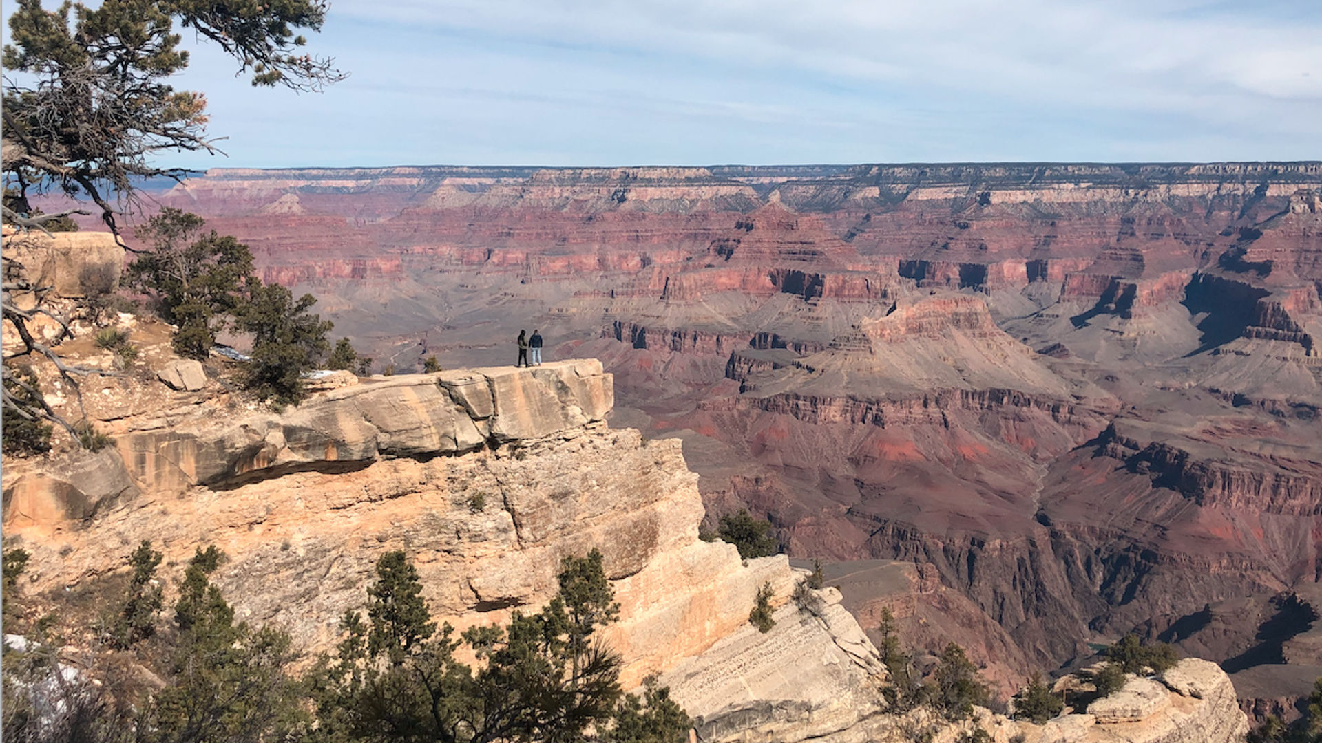 Twee mensen staan aan de rand van een krater en kijken uit over de Grand Canyon in Arizona.
