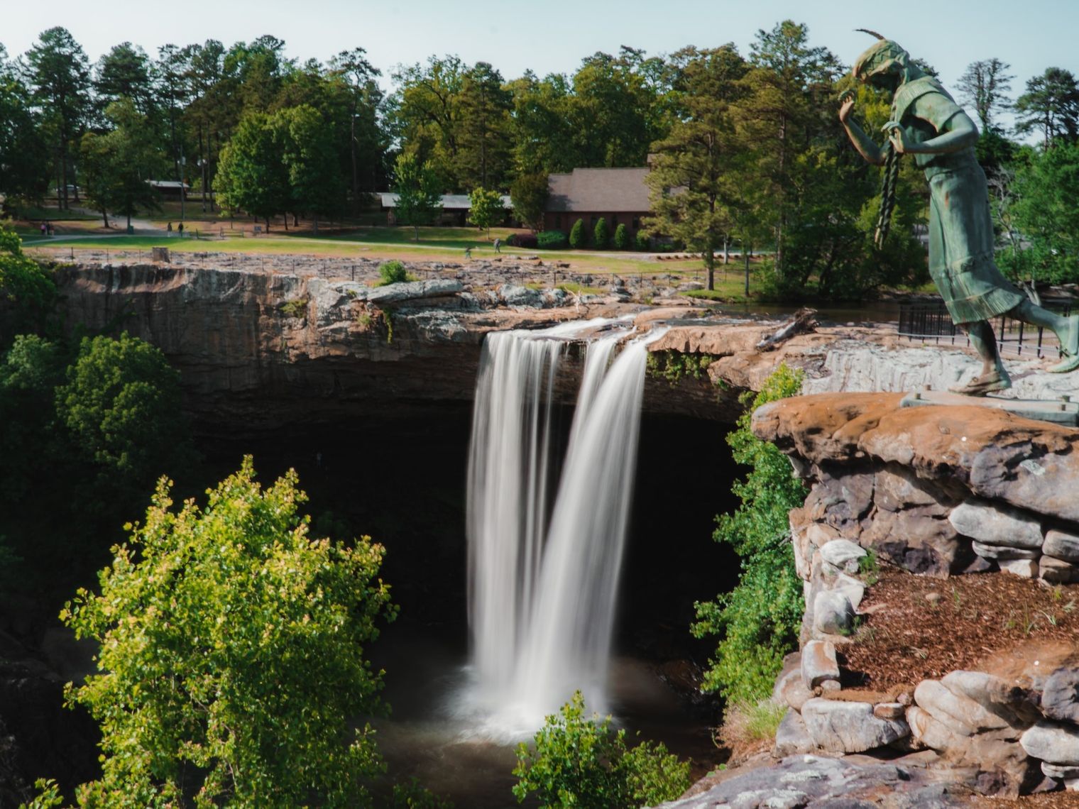 Noccalula Falls in Alabama mit Wasserfall, Felsklippe und einer Bronzestatue in