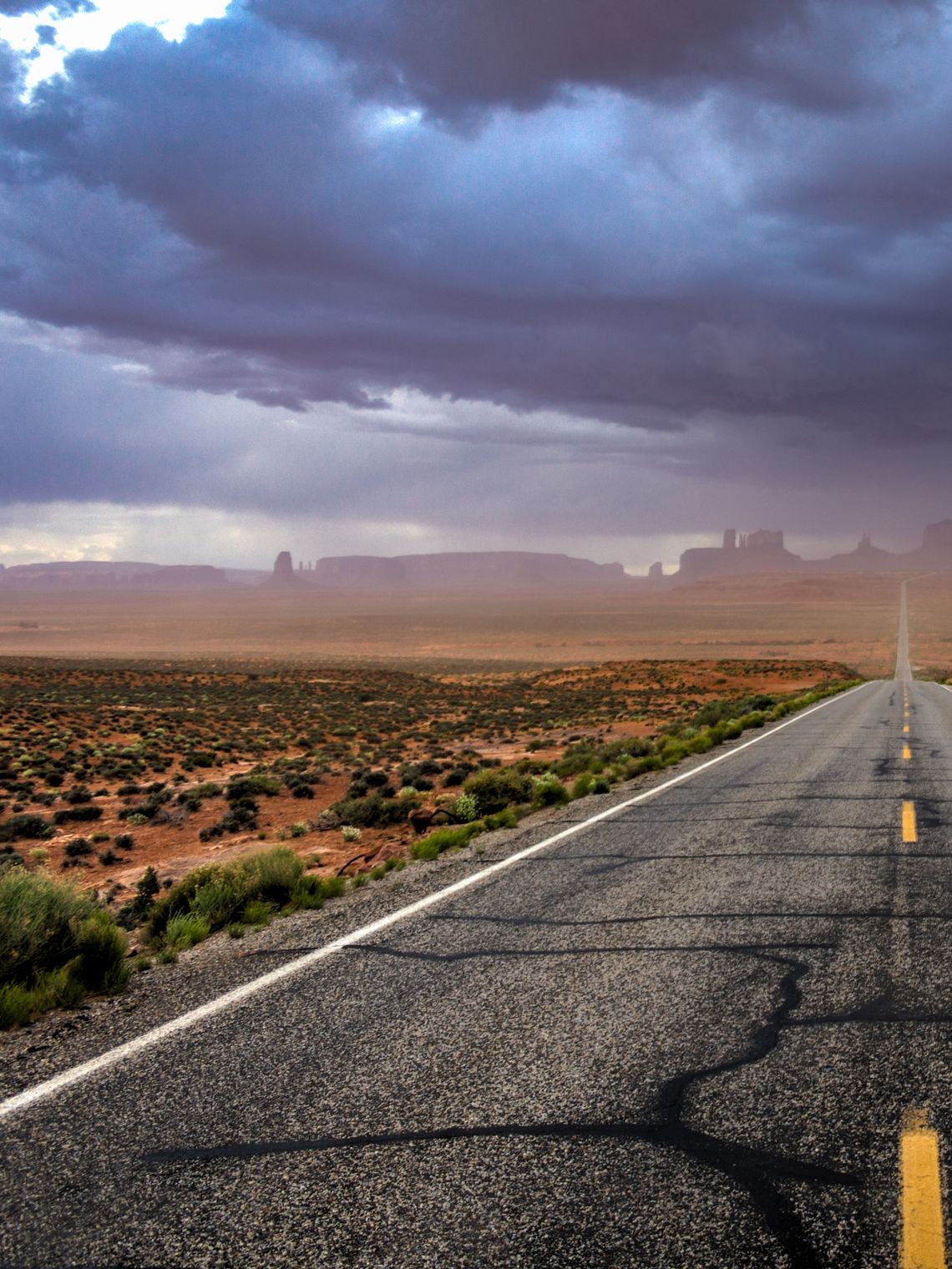 Straße mit Monument Valley im Hintergrund mit dunklem Himmel