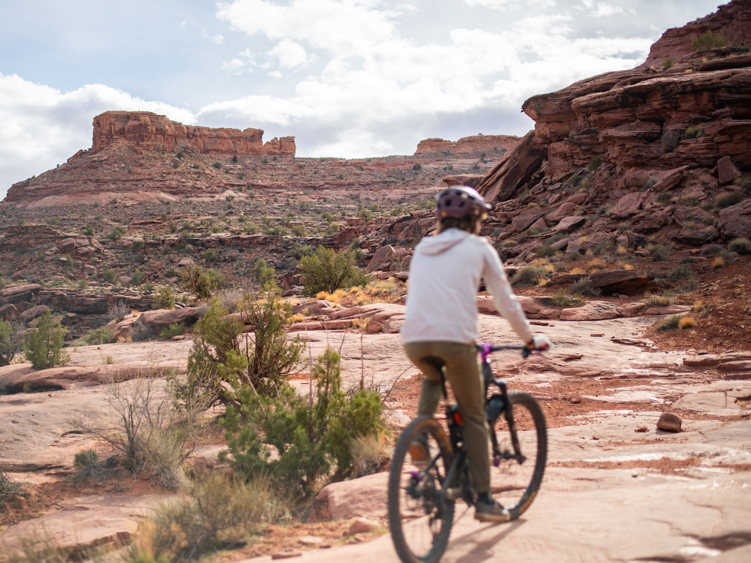 Eine Frau radelt durch Grand County in Utah, USA, umgeben von roten Felsformationen.