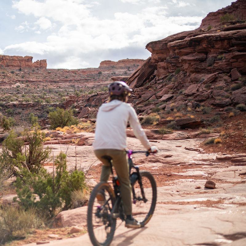 Eine Frau radelt durch Grand County in Utah, USA, umgeben von roten Felsformationen.