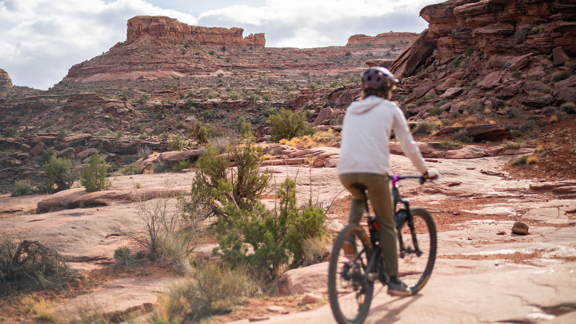Een dame fietst door Grand County in Utah, VS, omringd door rode rotsformaties.