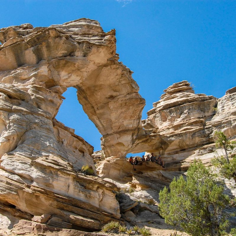 Menschen sitzen unter großem Felsbogen in Utah